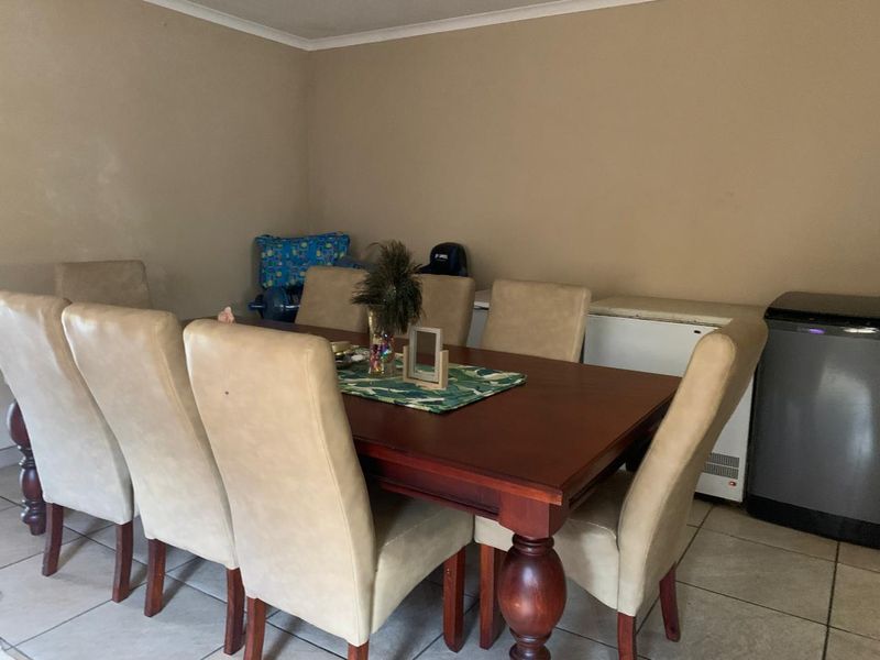 A dining area featuring ceramic floor tiles and neutral wall paint, providing a functional space for family meals.