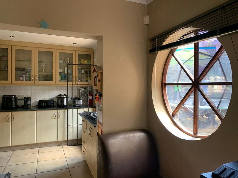 A functional kitchen featuring built-in cabinetry, a tiled backsplash, and a distinctive circular window that provides natural light.