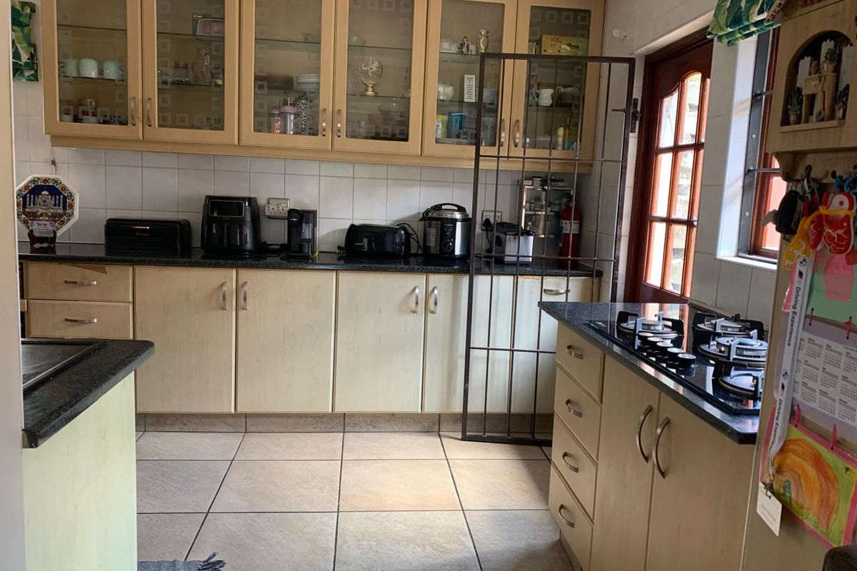 A functional kitchen featuring light wood cabinetry, granite countertops, a gas hob, and tiled flooring, offering a practical layout for daily meal preparation.