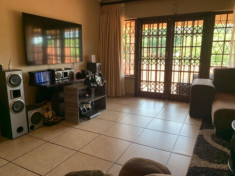 A living room featuring tiled flooring and a sliding glass door with a security gate, providing access to the exterior.