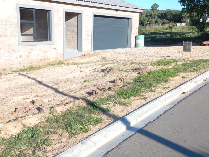 Front elevation of a newly constructed house featuring brick facade, aluminium windows, and a single garage, currently awaiting landscaping completion.