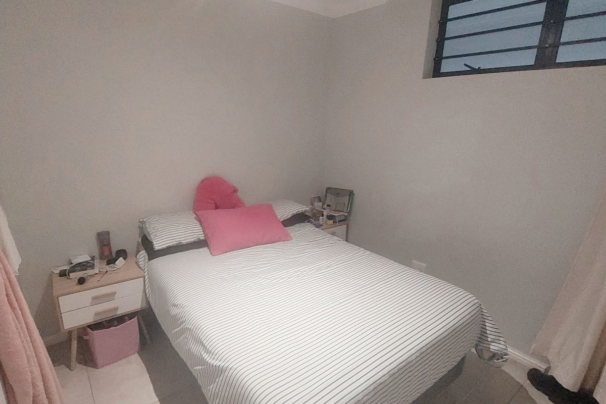 A compact bedroom featuring tiled flooring and a high-set horizontal window, providing a functional and neutral living space.