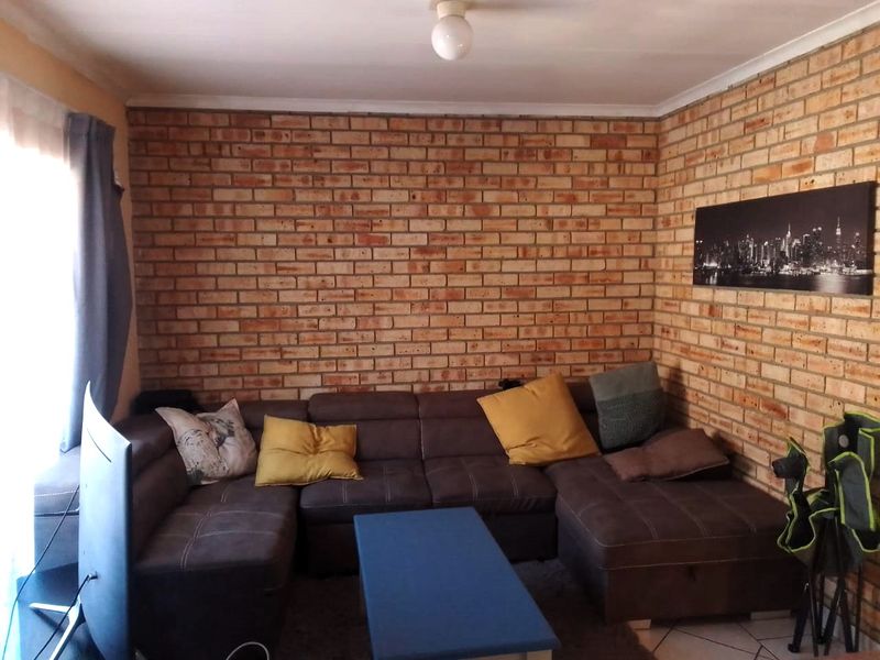 A living room featuring a prominent exposed brick feature wall and tiled flooring, offering a rustic aesthetic.