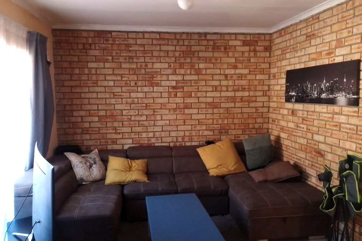 A living room featuring a prominent exposed brick feature wall and tiled flooring, offering a rustic aesthetic.