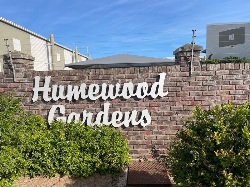 Entrance signage for Humewood Gardens featuring a brick boundary wall with integrated electric fencing.