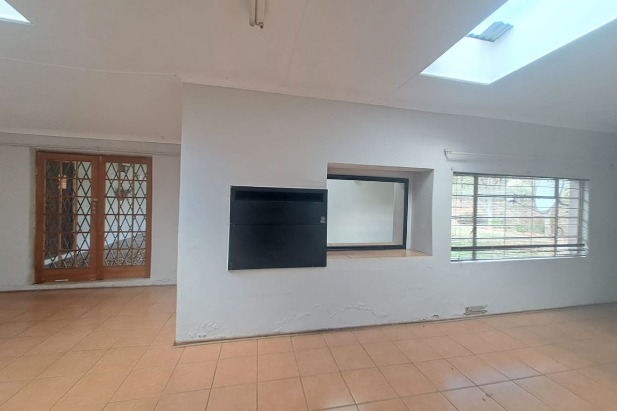 Spacious living area featuring tiled flooring, a built-in fireplace, and natural light provided by multiple skylights and large windows.