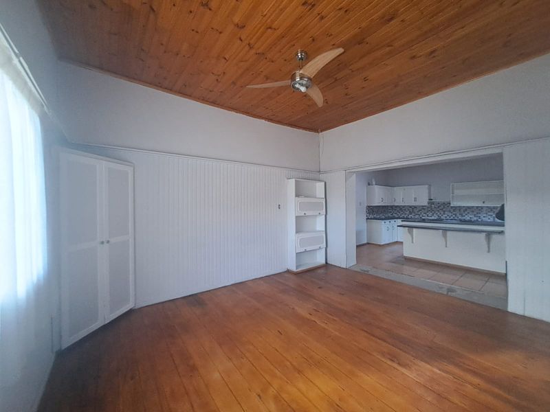 Open plan living area featuring timber flooring and ceiling, with an adjoining kitchen space. The area is vacant and ready for staging.