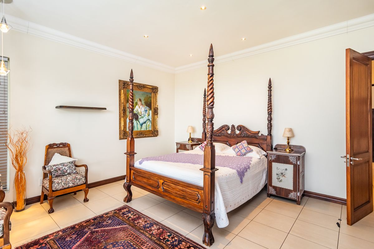 A spacious bedroom featuring neutral tiled flooring, recessed downlighting, and elegant crown molding, providing a clean and well-maintained living space.