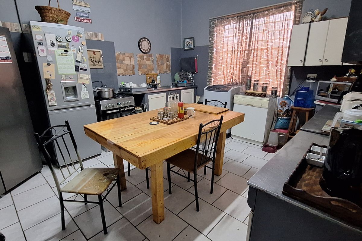 A functional kitchen featuring tiled flooring, built-in cabinetry, and a central dining area, providing a practical space for daily meal preparation and dining.