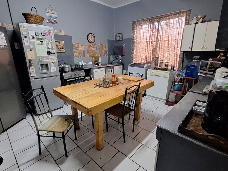 A functional kitchen featuring tiled flooring, built-in cabinetry, and a central dining area, providing a practical space for daily meal preparation and dining.