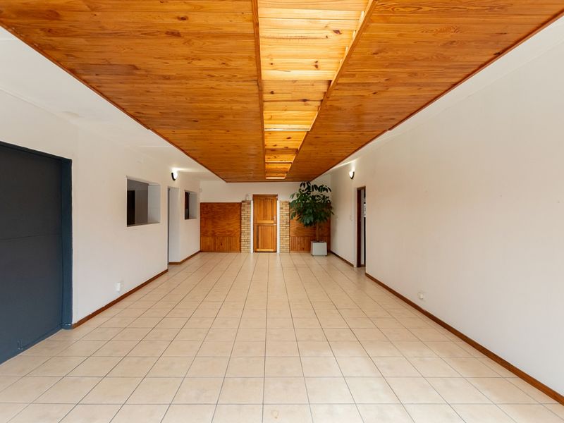 Spacious living area featuring a distinctive timber tongue and groove ceiling, ceramic tiled flooring, and timber wall paneling details.