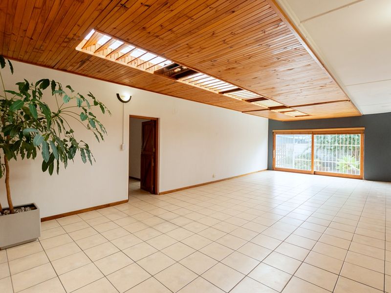 Spacious living area featuring a unique timber slat ceiling with integrated skylights, tiled flooring, and large sliding glass doors providing natural light.