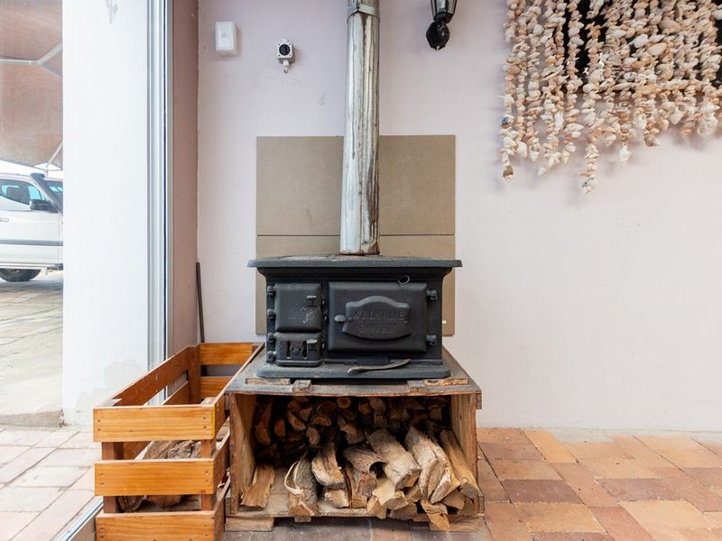Covered patio area featuring a cast iron wood burning stove with flue pipe and durable brick paved flooring.