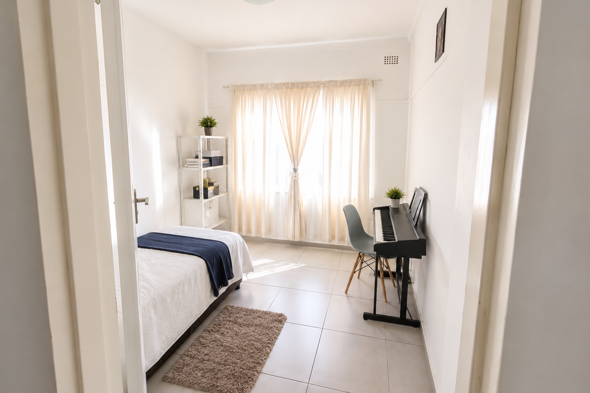 A bright and well-maintained bedroom featuring neutral tiled flooring and natural light, offering a clean and functional space.