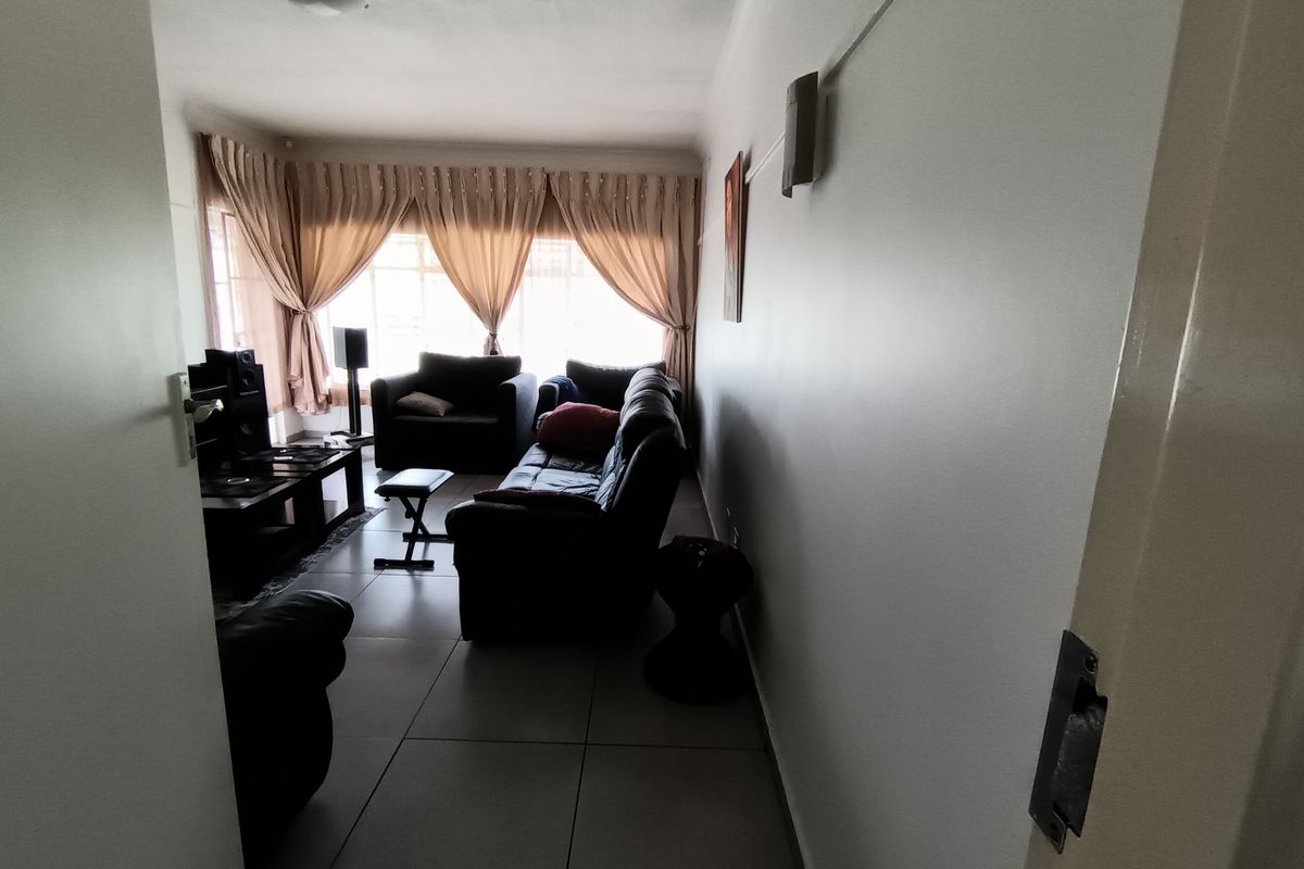 A living room featuring tiled flooring and large windows with curtain tracks, offering a functional space with natural light.