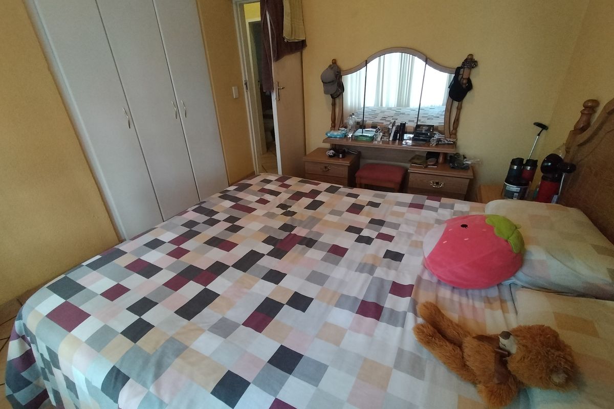 A functional bedroom featuring built-in cupboards and tiled flooring, providing a practical layout for comfortable living.