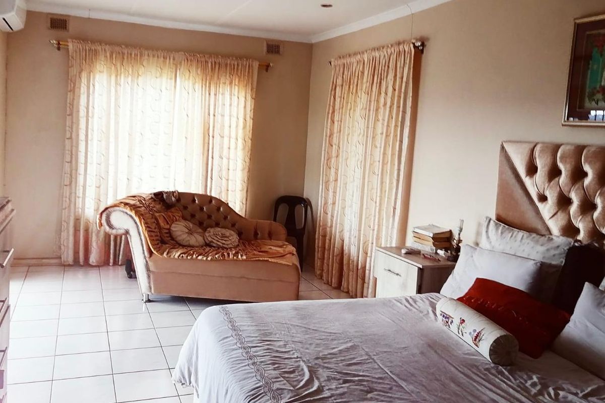 A spacious bedroom featuring tiled flooring, recessed downlighting, and an integrated air conditioning unit, offering a neutral base for personalization.