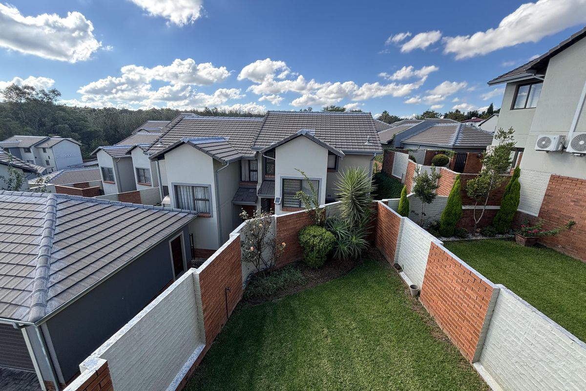 An elevated aerial view of a cluster property complex, showcasing the tiled roofs, private garden areas, and brick boundary walls.