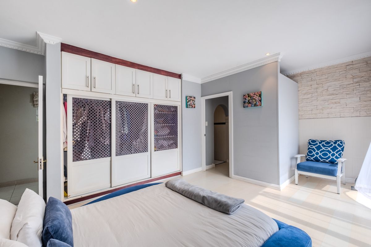 A well-maintained bedroom featuring built-in floor-to-ceiling cabinetry with lattice-style sliding doors, crown molding, and a decorative stone-cladding feature wall.