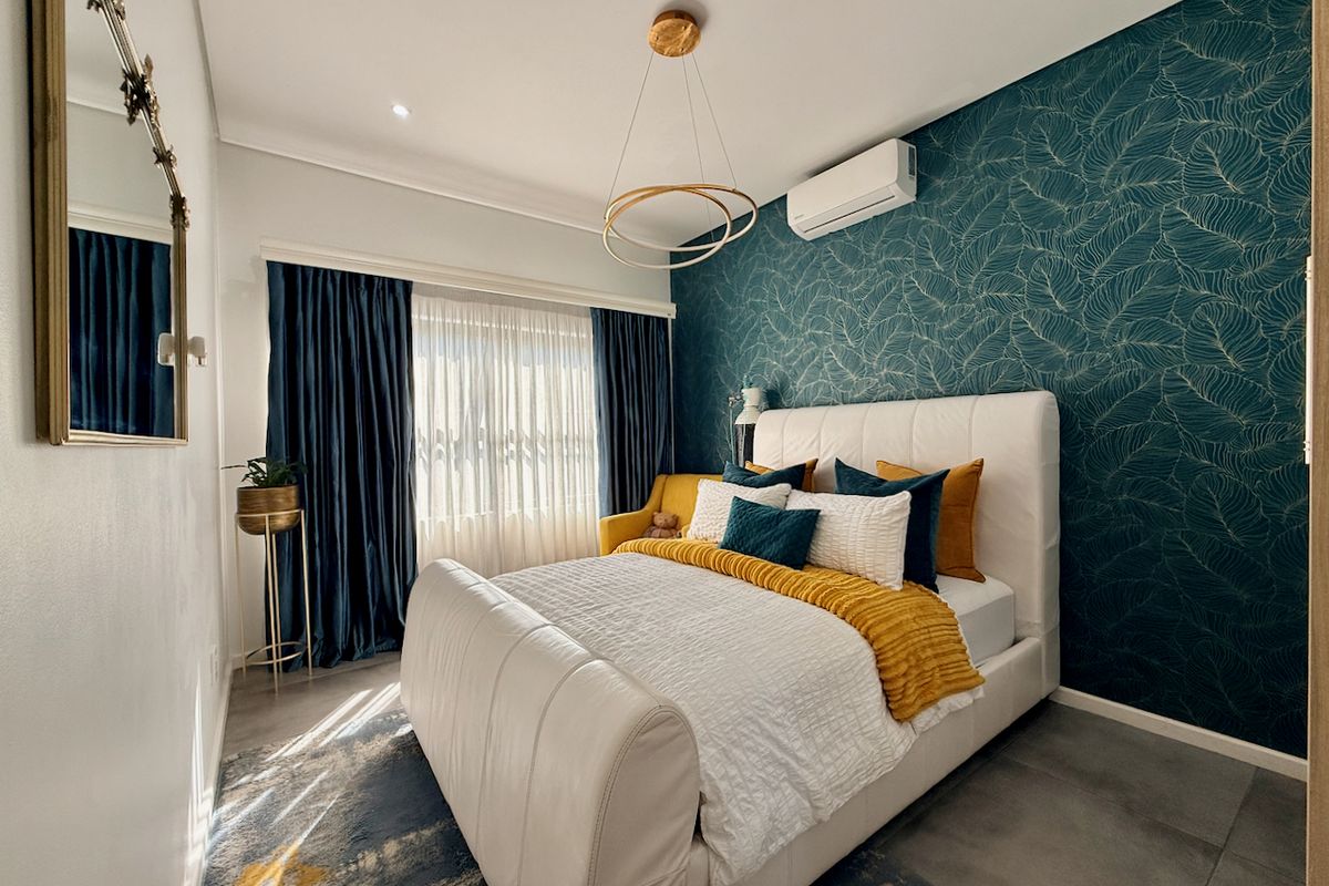 A well-appointed bedroom featuring a bold patterned feature wall, split-system air conditioning, modern tiled flooring, and recessed lighting.