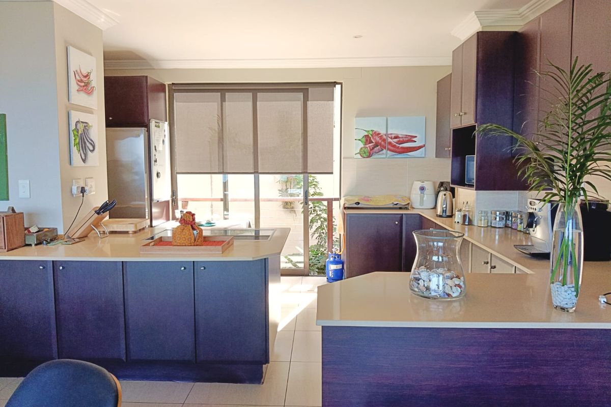 A functional kitchen featuring dark wood cabinetry, stone countertops, and direct access to an outdoor area through a sliding glass door.