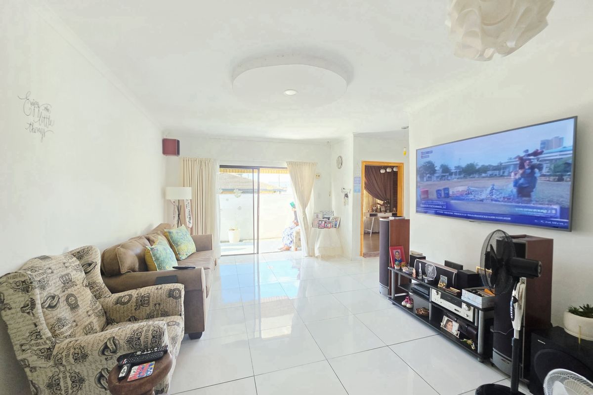 A bright living room featuring large format floor tiles, neutral walls, and a sliding glass door providing access to the exterior.
