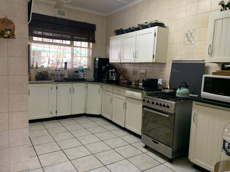 Functional kitchen featuring white cabinetry, tiled flooring, a gas stove, and ample counter space, offering a practical layout for daily meal preparation.