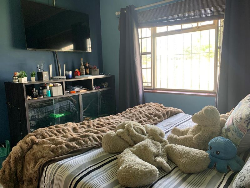 A bedroom featuring blue walls, a window with security bars, and a curtain rod.