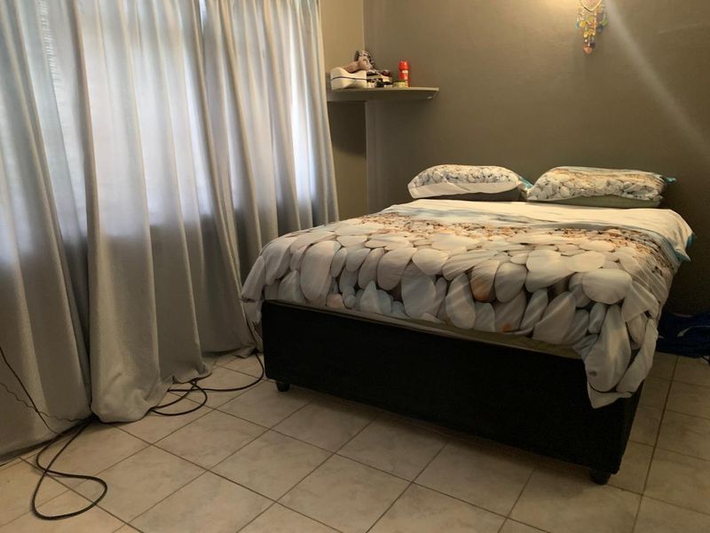 A bedroom featuring tiled flooring and a built-in wall shelf, providing a functional space with neutral wall tones.