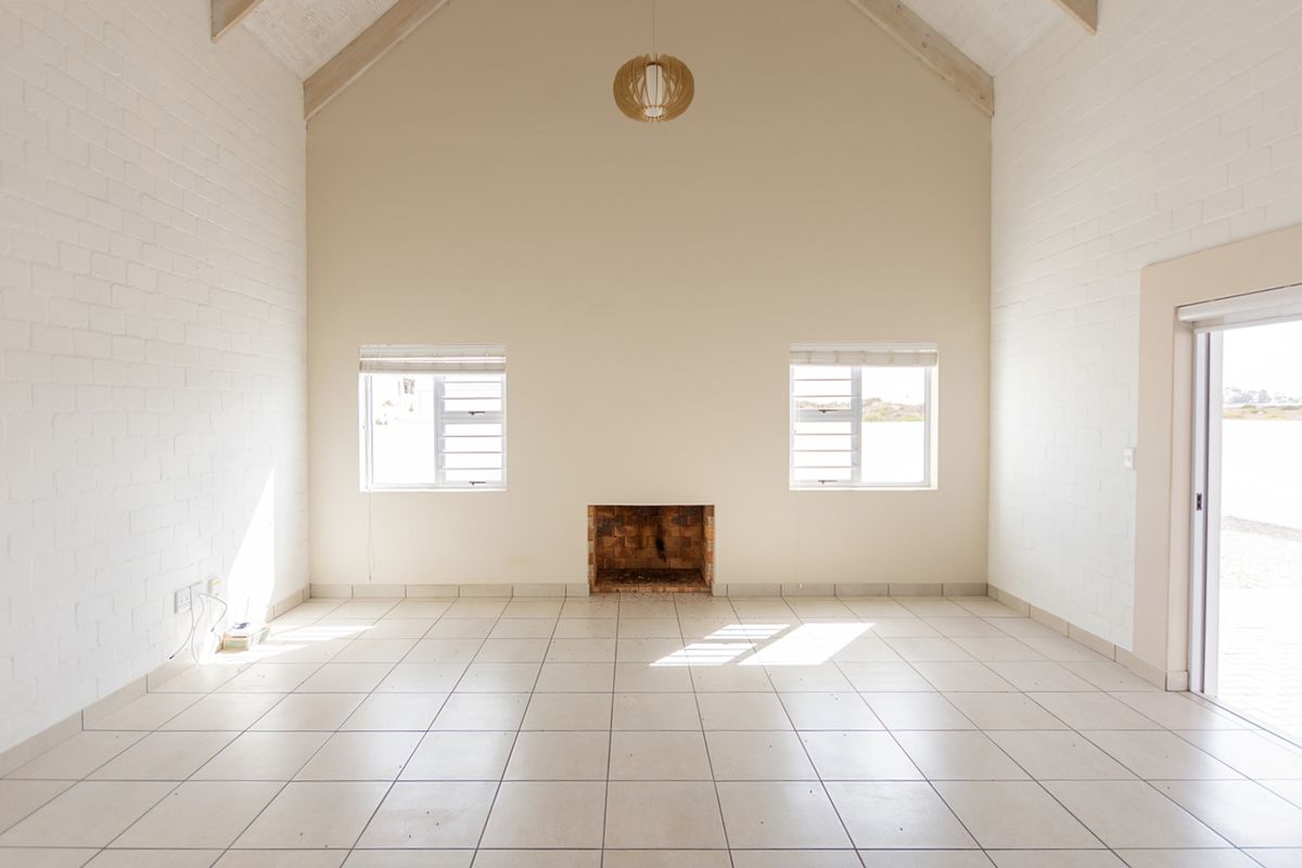 Spacious living area featuring a vaulted ceiling, tiled floors, and a built-in brick fireplace, offering a bright and open atmosphere.