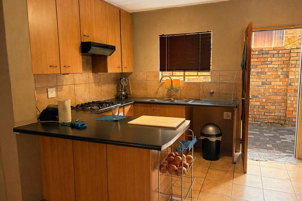 Functional kitchen featuring wood-look cabinetry, gas hob, extractor fan, and direct access to an outdoor paved courtyard area.