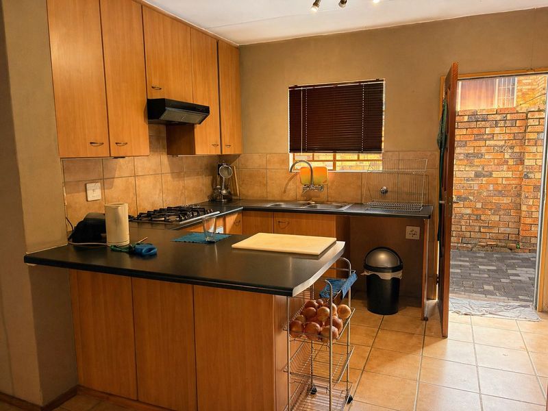 Functional kitchen featuring wood-look cabinetry, gas hob, extractor fan, and direct access to an outdoor paved courtyard area.