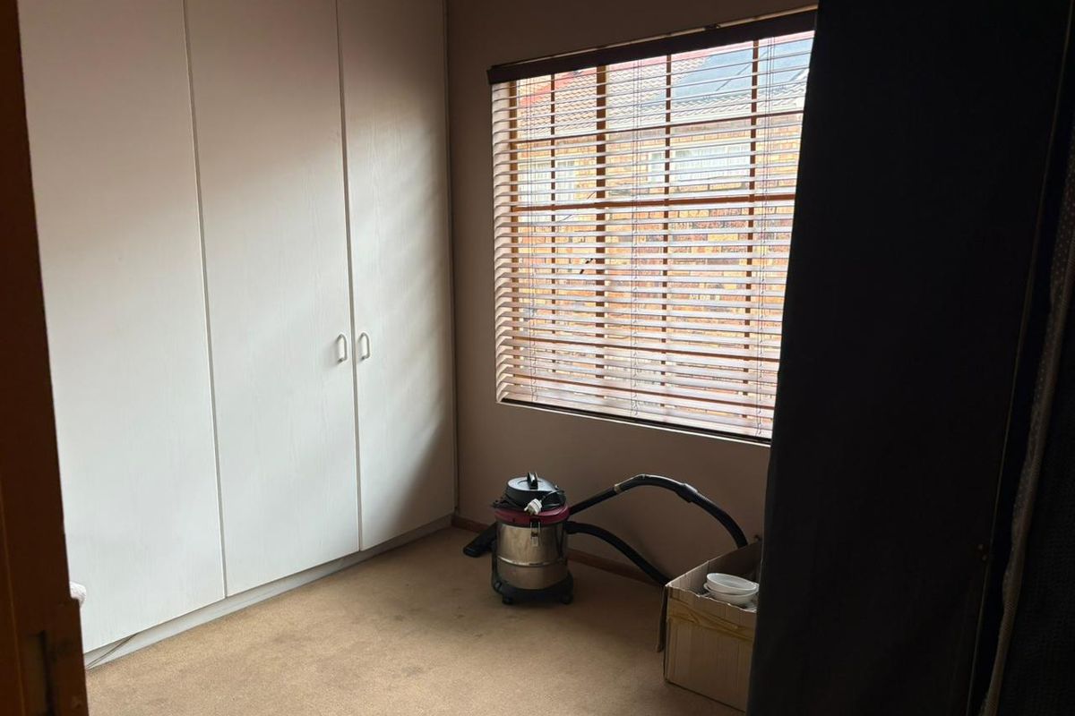 A bedroom featuring built-in cupboards and venetian blinds, offering a functional space ready for personalization.