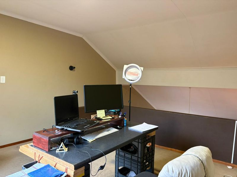 A functional office space featuring a sloped ceiling and neutral wall finishes, suitable for a home workspace or study area.