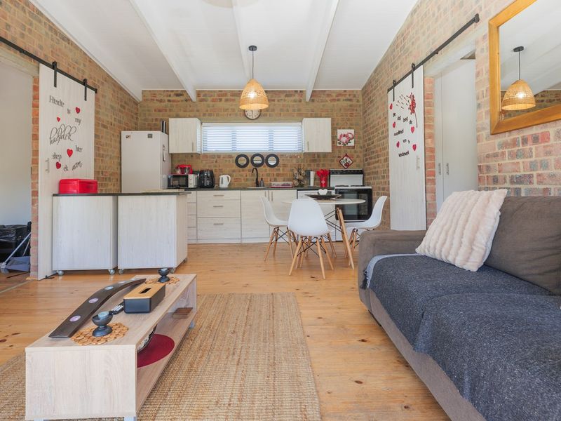 Open-plan living and kitchen area featuring exposed brick walls, timber flooring, exposed beam ceilings, and sliding barn doors.