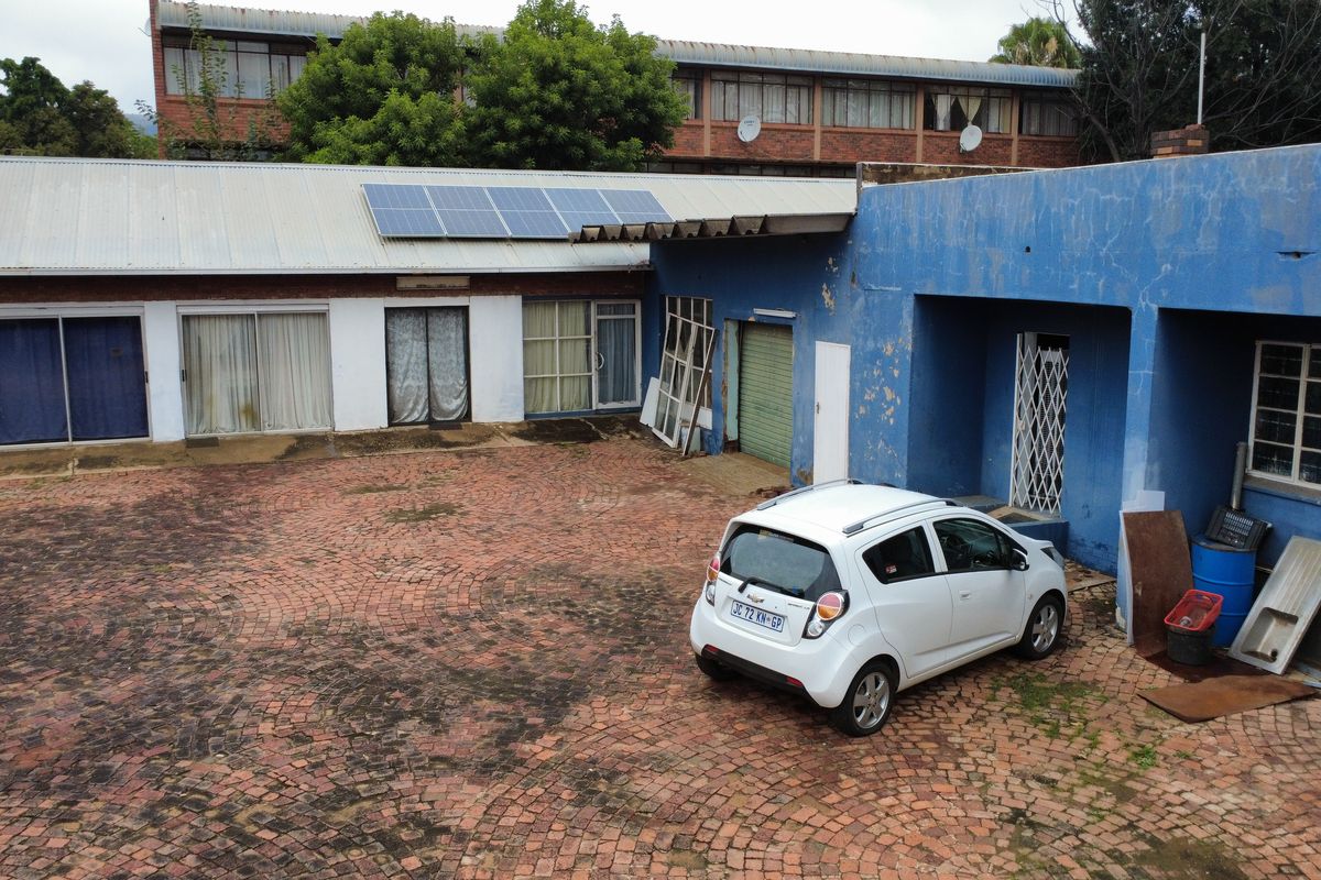 Rear courtyard area featuring brick paving, solar panels on the roof, and multiple access points to the main building structure.