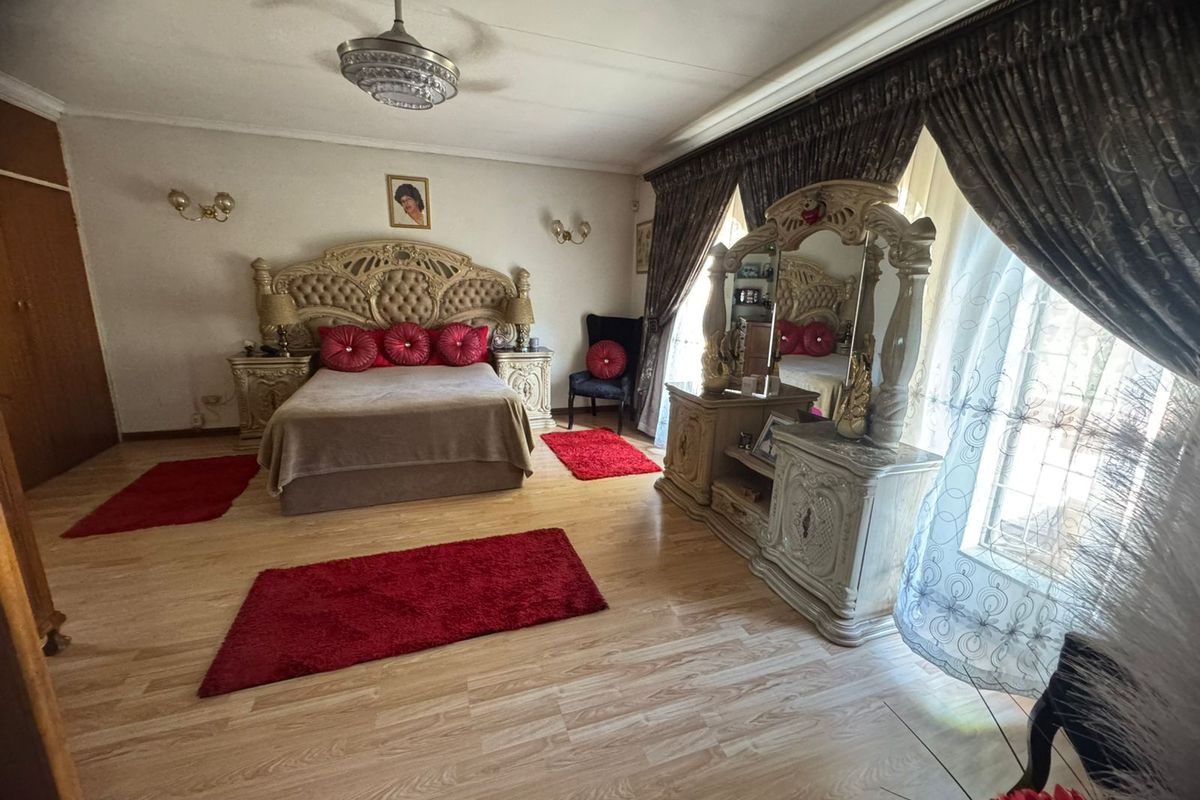 Spacious bedroom featuring light-toned laminate flooring, a ceiling fan with integrated lighting, and wall-mounted sconces, offering a functional and well-lit sleeping area.