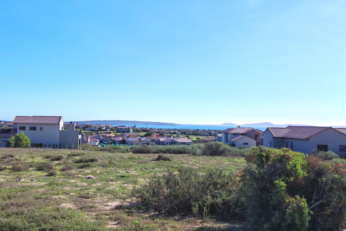 A scenic view overlooking a residential neighborhood with coastal landscape and distant water views.