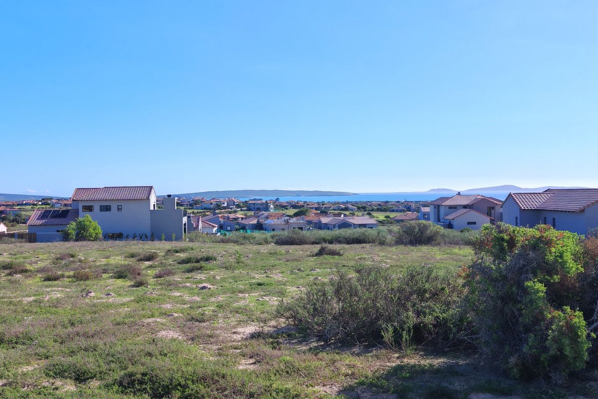 A scenic view overlooking a residential neighbourhood with coastal landscape in the distance, showcasing the surrounding environment of the vacant land.