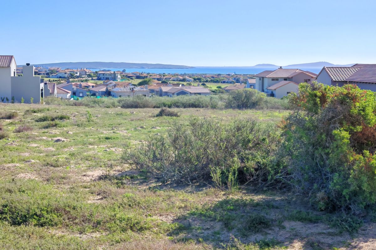 A scenic view overlooking a residential estate with coastal landscape and distant ocean horizon.