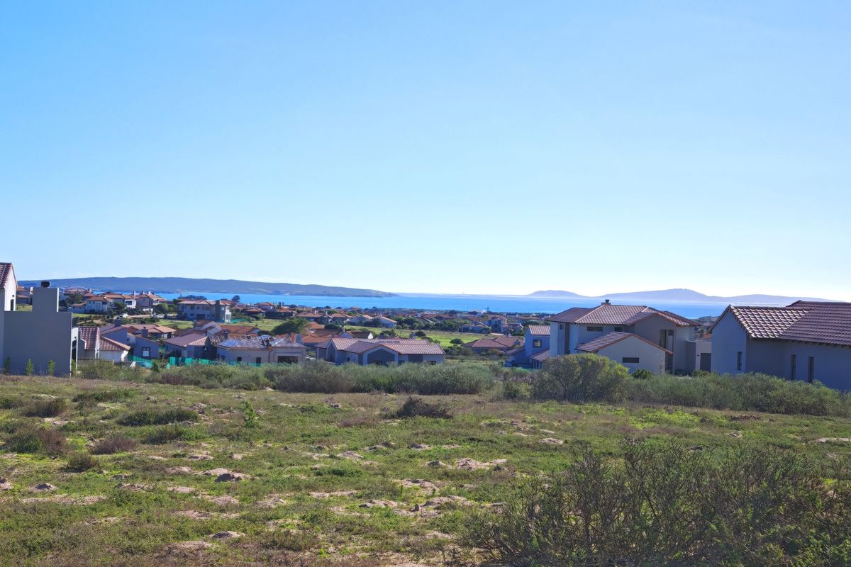 A scenic elevated view overlooking a residential coastal estate with distant ocean and mountain vistas.