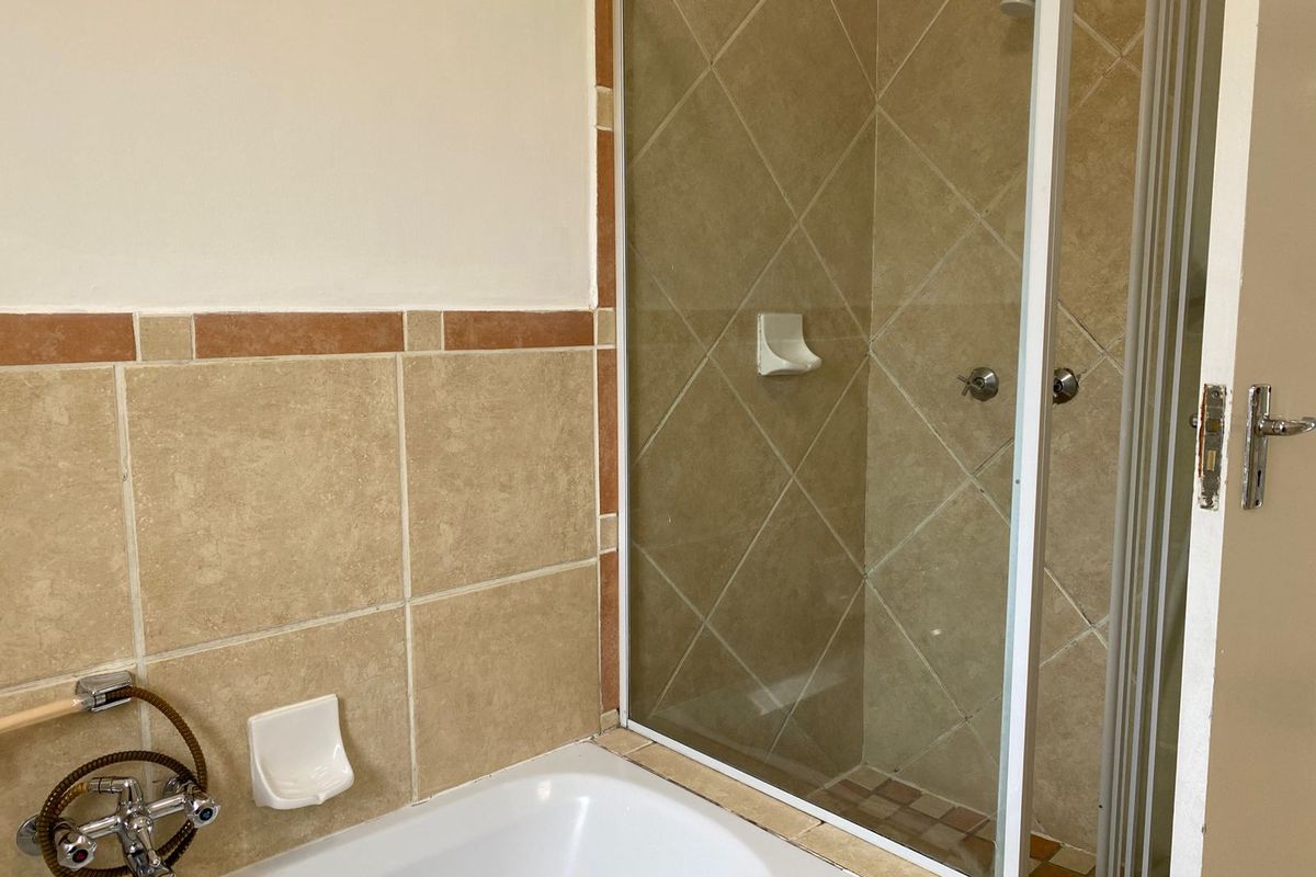A functional bathroom featuring a built-in bathtub and a separate shower enclosure with tiled walls and standard fixtures.