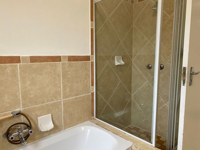 A functional bathroom featuring a built-in bathtub and a separate shower enclosure with tiled walls and standard fixtures.