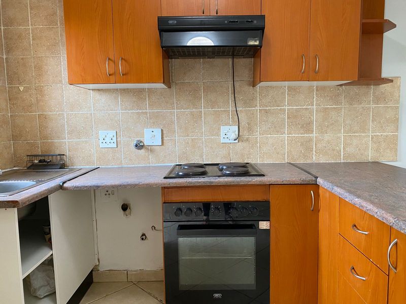 A functional kitchen featuring wood-look cabinetry, tiled backsplash, and built-in appliances, currently requiring minor repairs and cosmetic updates to improve its overall condition.