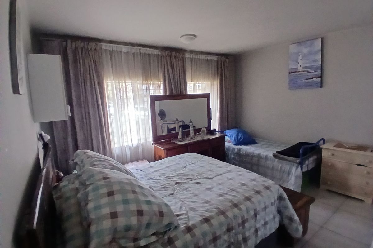 A functional bedroom featuring tiled flooring and window treatments, offering a comfortable space for rest.