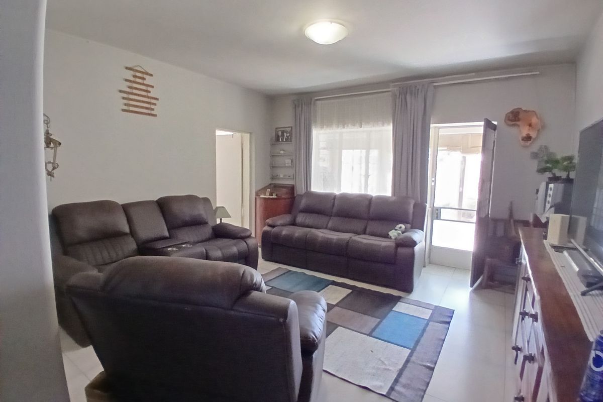 A living room area featuring tiled flooring and natural light access through a glass door leading to an outdoor space.