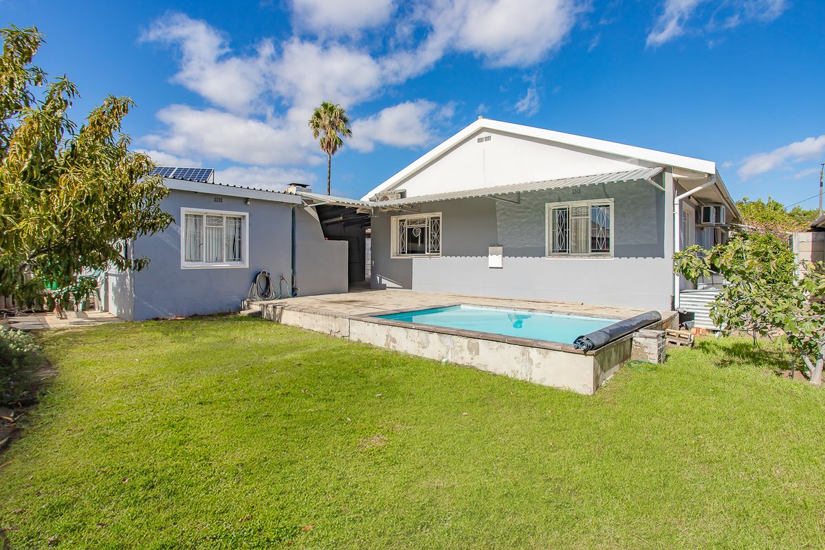 Rear exterior view of the house featuring a swimming pool, paved patio area, and solar panels installed on the roof.