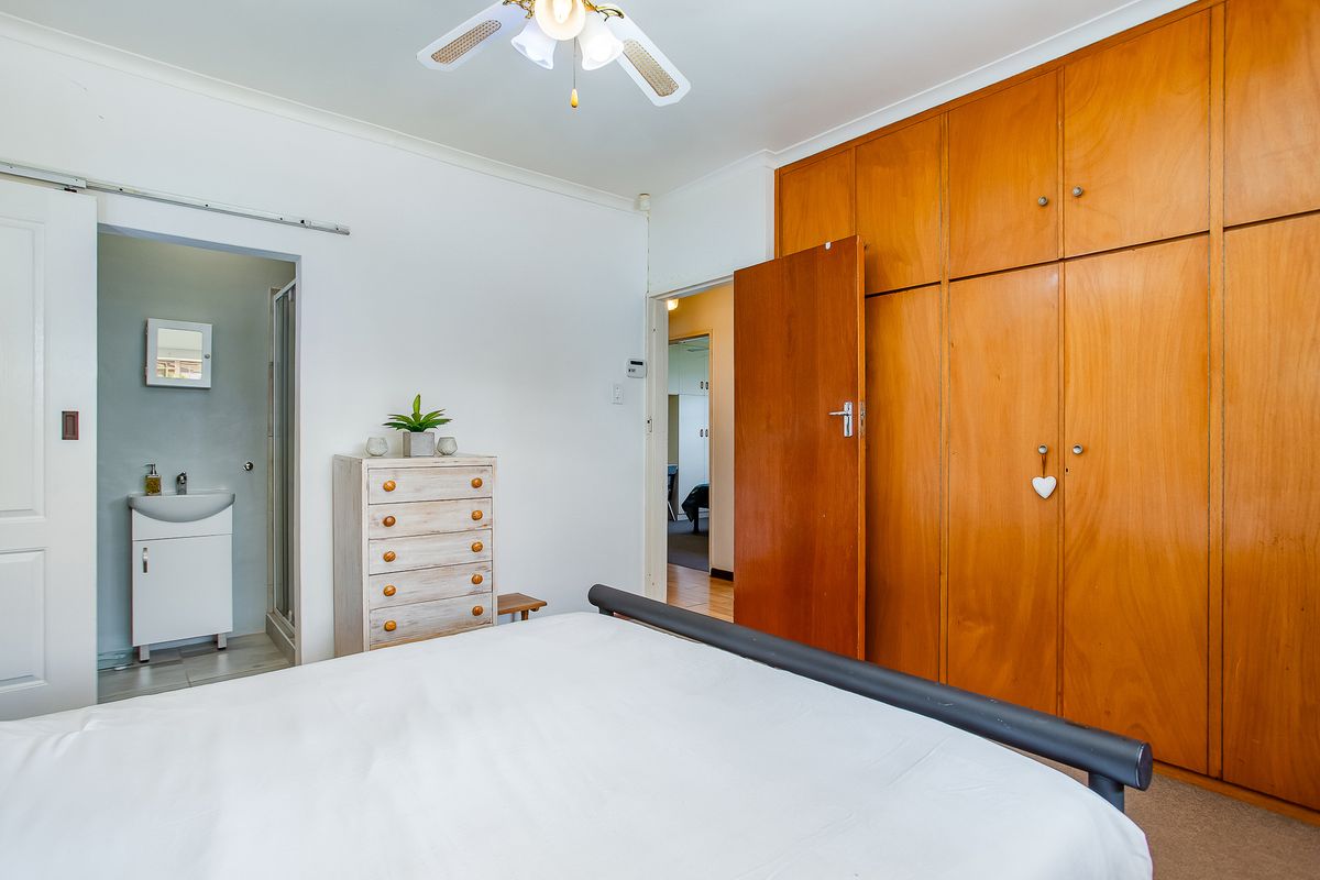 Bedroom featuring built-in wooden cupboards, a ceiling fan, and direct access to an en-suite bathroom.
