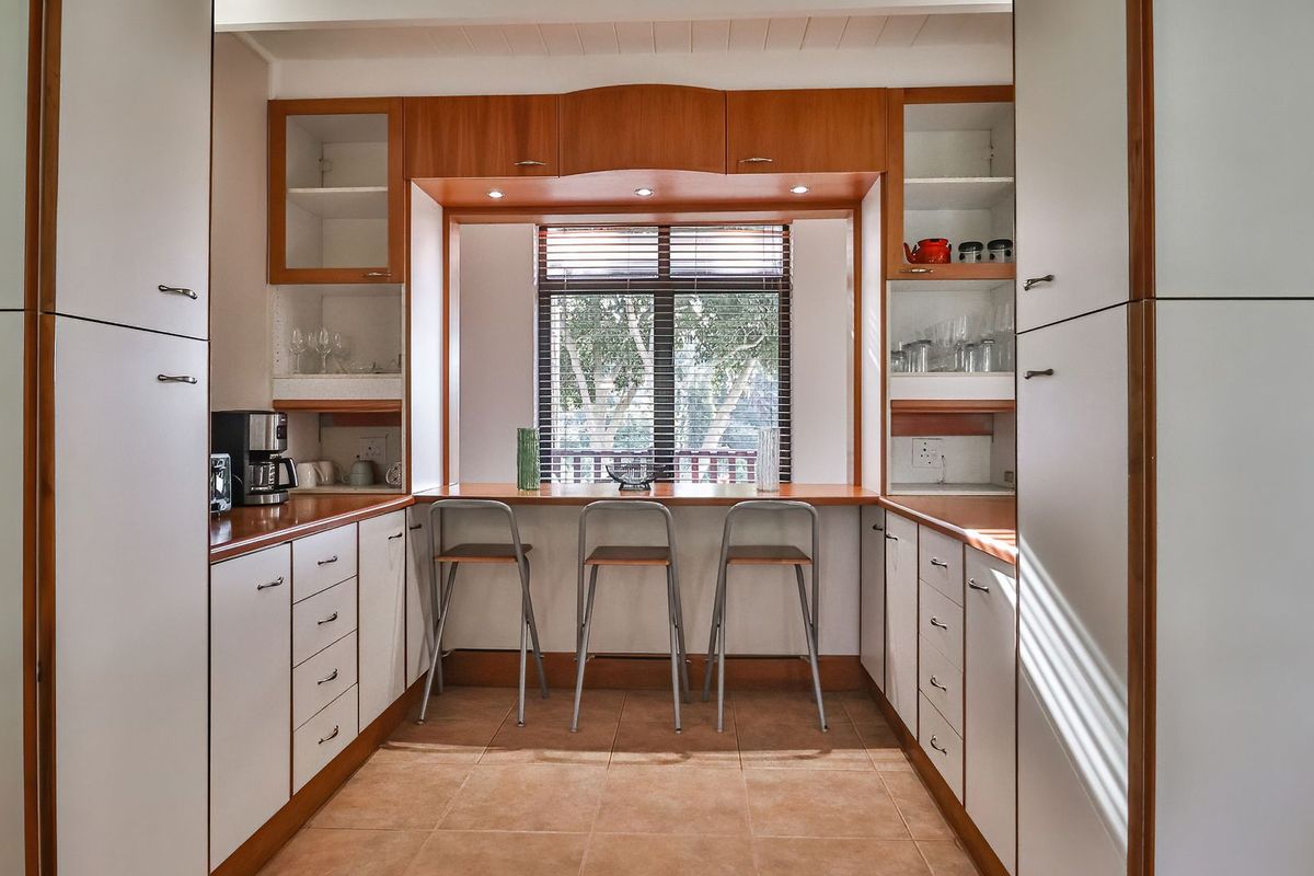 A functional kitchen featuring built-in cabinetry, a central breakfast bar with window views, and tiled flooring.