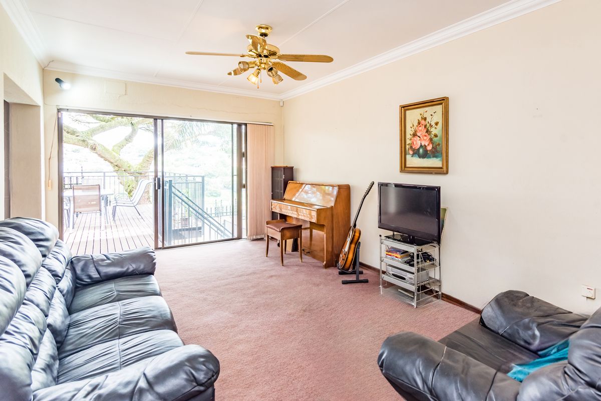 Spacious living room featuring neutral walls, carpet flooring, crown molding, and a large sliding glass door providing access to an outdoor deck area.